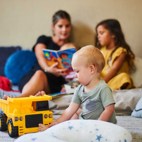 Younger child playing older child reading with teacher