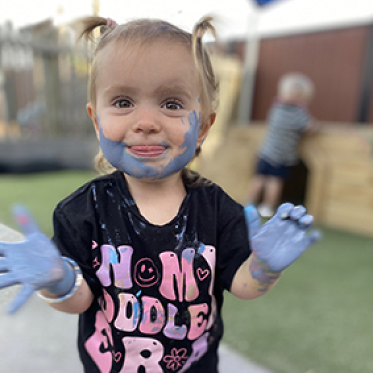 Under 2 girl enjoying paint fun outdoors