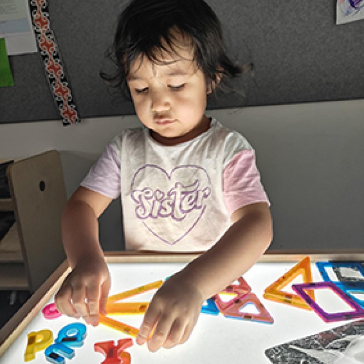 young child enjoying light table indoors at Busy Bees Aoraki