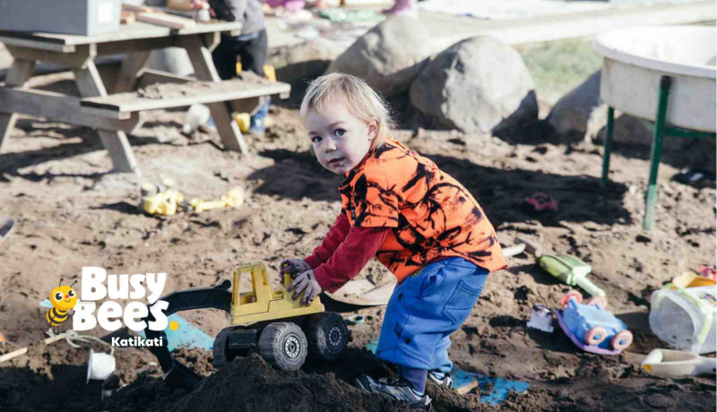 Toddler boy playing in large outdoor sandpit at Busy Bees Katikati
