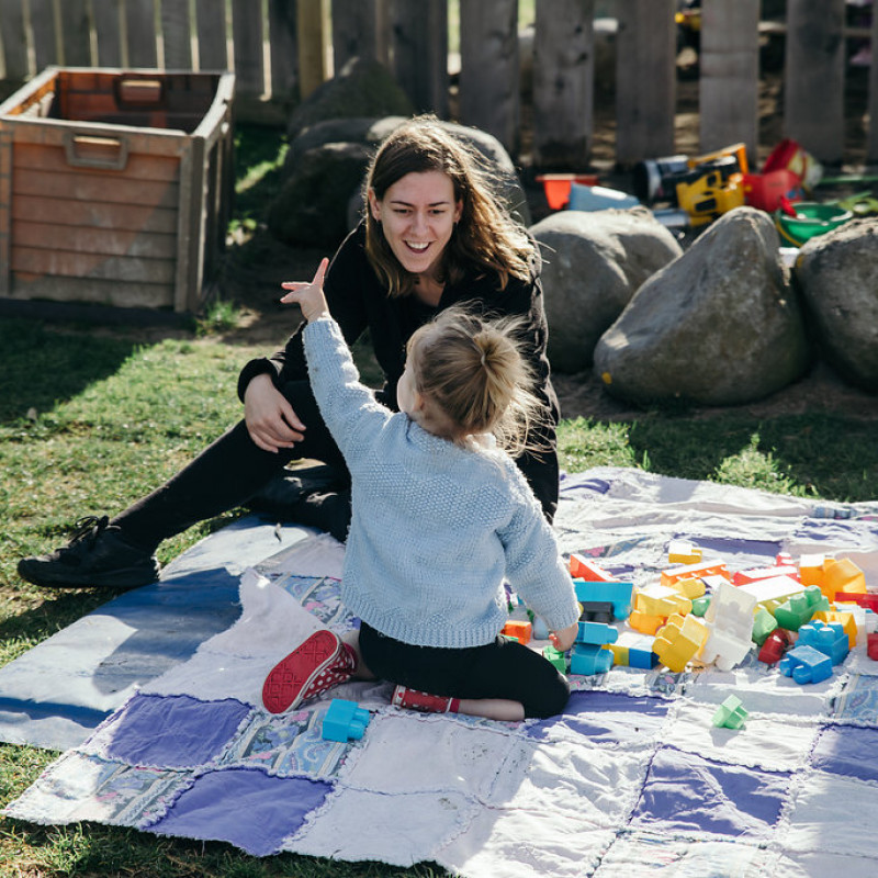 Child and teacher at play - large outdoor area at Busy Bees Katikati