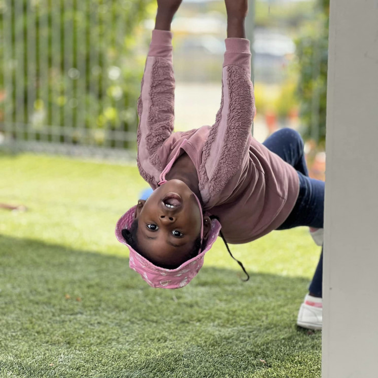Young girl swinging on the outdoor play gym at Busy Bees Ormiston Road