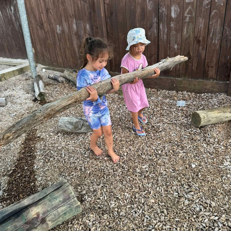 Busy Bees Papamoa Beach Girls helping each other carry log