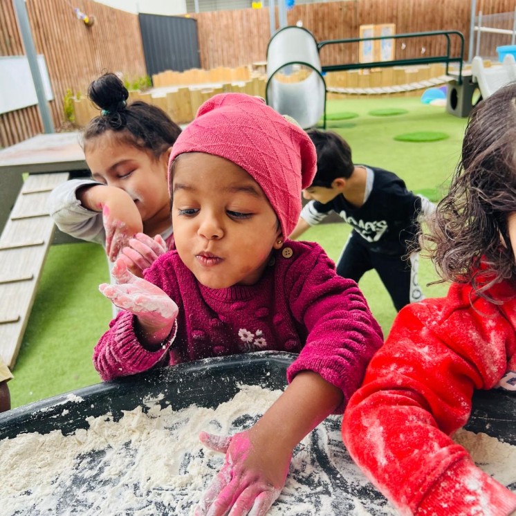 Girl having fun outside with messy sensory play at Busy Bees Te Rapa