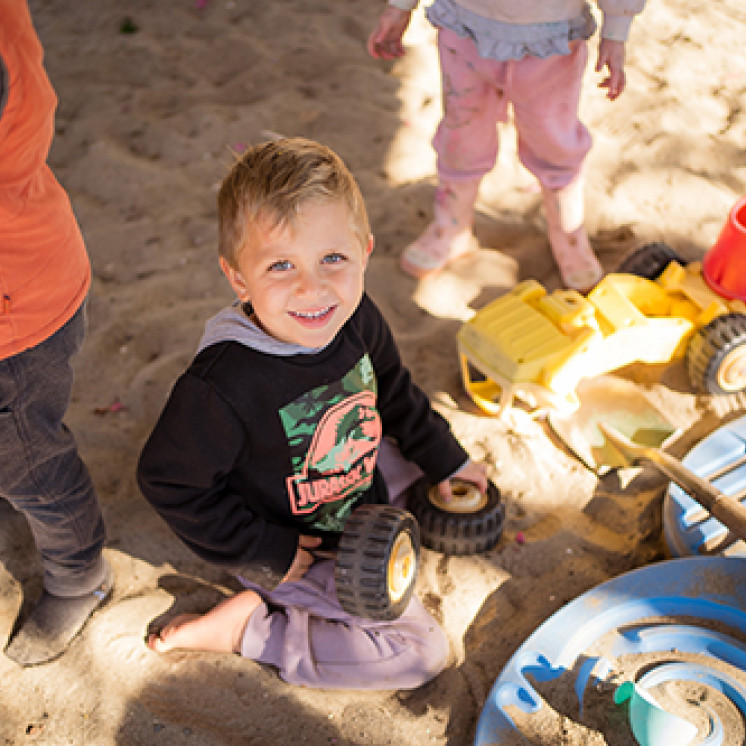 Boy playing with trucks in sand pit at Busy Bees Western Heights