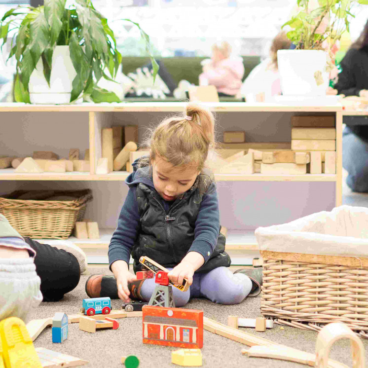 Girl playing with wooden train set at Busy Bees Tairāwhiti childcare in Gisborne