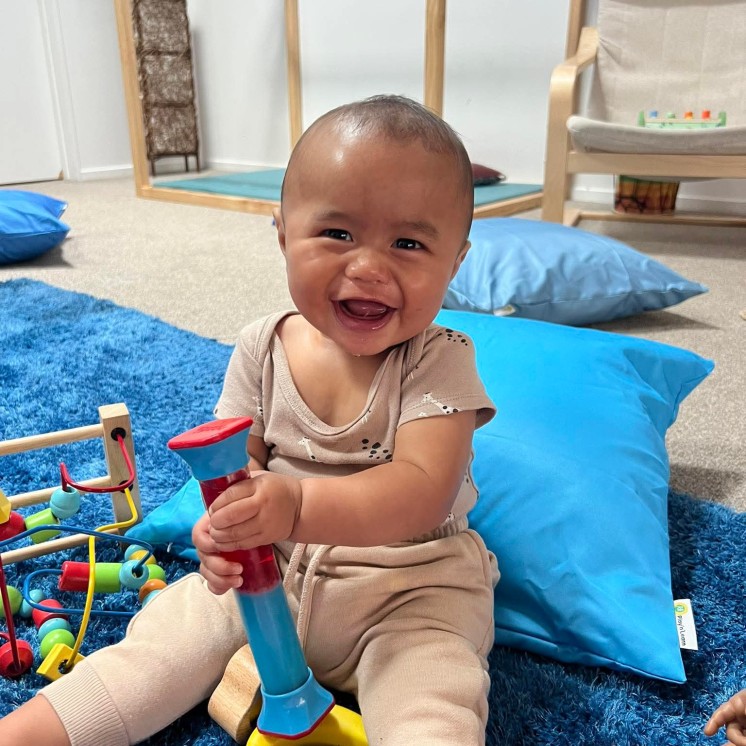 Busy Bees Tairāwhiti childcare in Gisborne baby playing and smiling 
